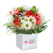 A joyful spirit infuses this luxe bouquet, gathered in the heart of Surrey Quays and presented in a refined square white gift bag. Plump coral and peach carnations, their frilled petals full of soft energy, mingle among snowy white daisies with vibrant green-gold centers-each flower echoing the cheerful mood of the Market Square on a sunlit day. Cloudlike baby's breath drifts throughout the arrangement, lending a sense of innocence and gentle movement, while hints of purple-tinged blooms peep through on one side, sparking curiosity and depth. The flowers rest amid glossy, deep green foliage, carefully arranged to form a lush circular embrace, reminiscent of tree-lined paths winding around South Dock. The sturdy bag's crisp ribbon handles and professional finish convey the readiness of this bouquet for special moments-whether it's marking a birthday, an anniversary, or a spontaneous surprise for a loved one near the historic Surrey Docks. Crafted with passion by local florists, every detail invites admiration and delight, making this bouquet a memorable expression of Surrey Quays' community warmth and style.
